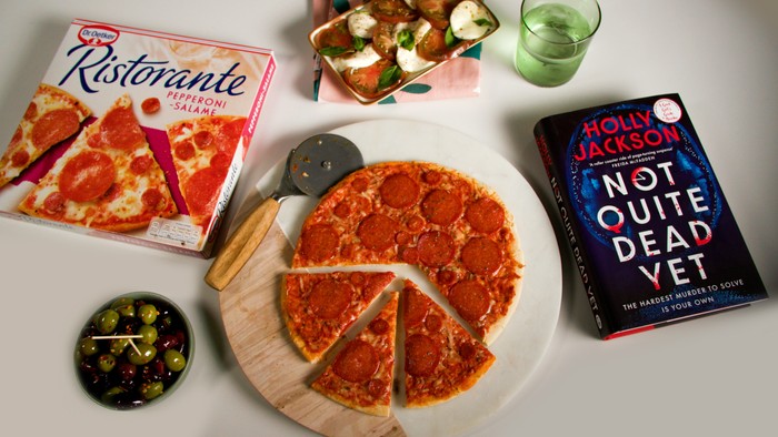 An image of a pepperoni pizza with a book next to it and a pizza box on the other side