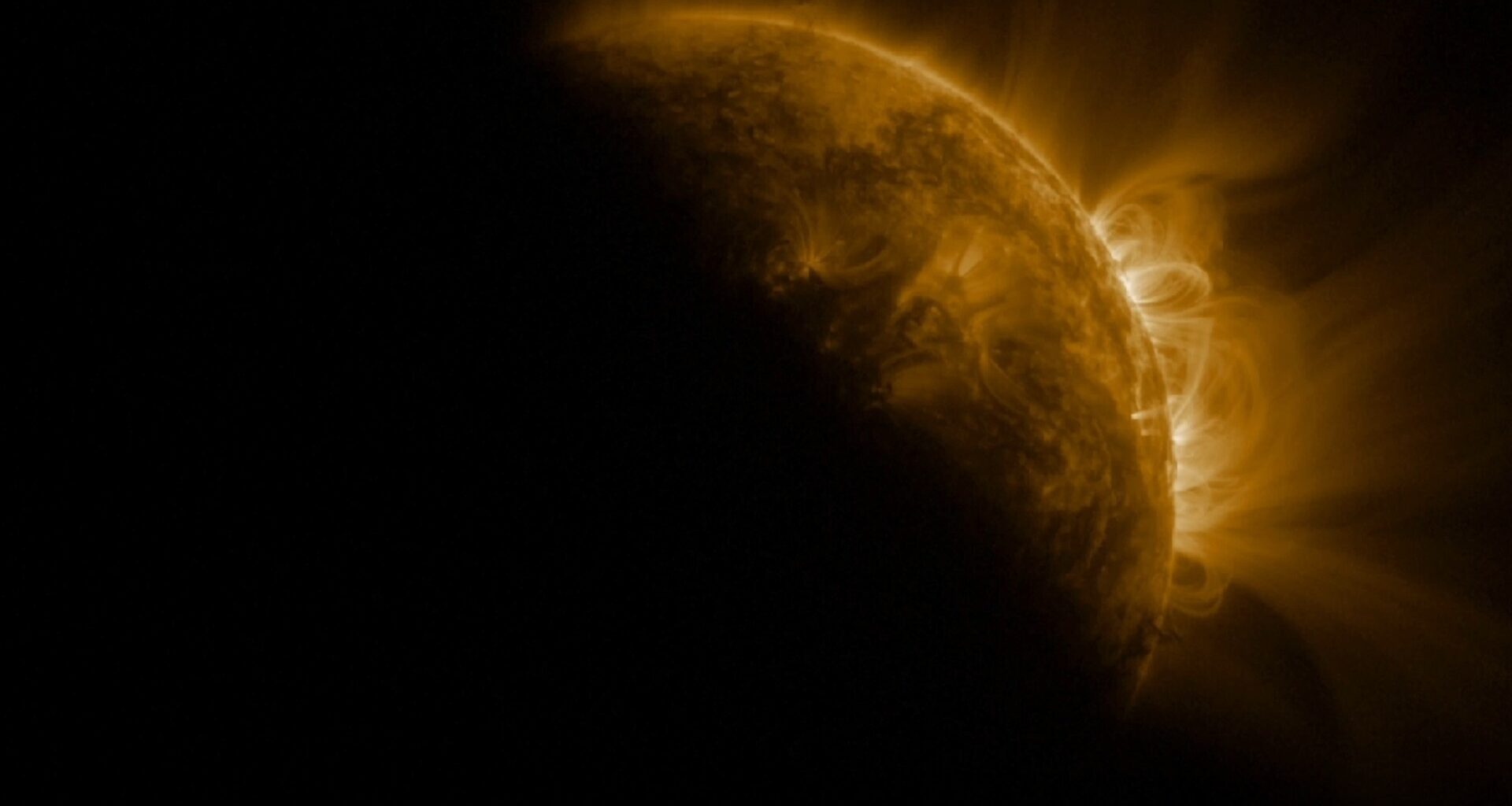 An image of the sun in space, with a dark shadow partially covering it where the moon crosses in front of it