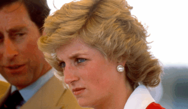 Princess Diana scowling wearing a red and white dress