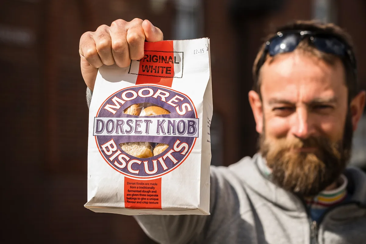 Bearded man holding a bag of 'Moores Biscuits - Dorset Knob'