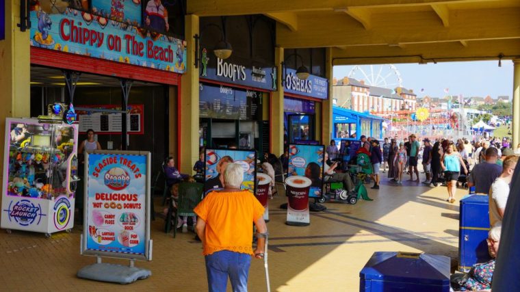 Barry Island, Barry, Wales, Aug 30 2024: People walk through the western shelter at Barry Island visiting the beach shops and amusement arcades made famous by Gavin and Stacey TV series.