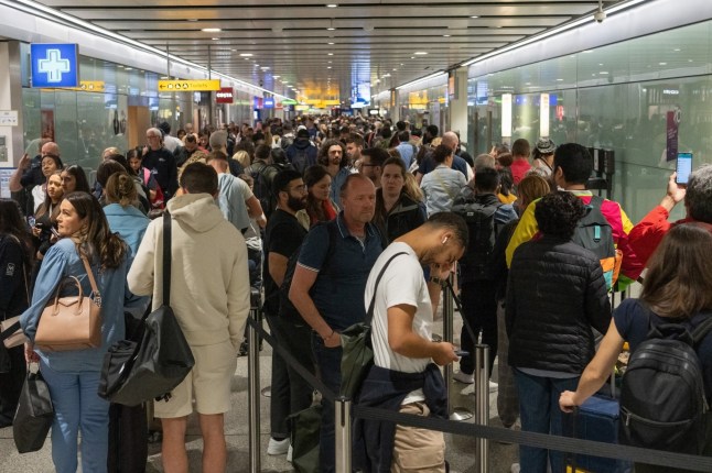 Travellers wait in a long queue to pass through the security check at Heathrow on June