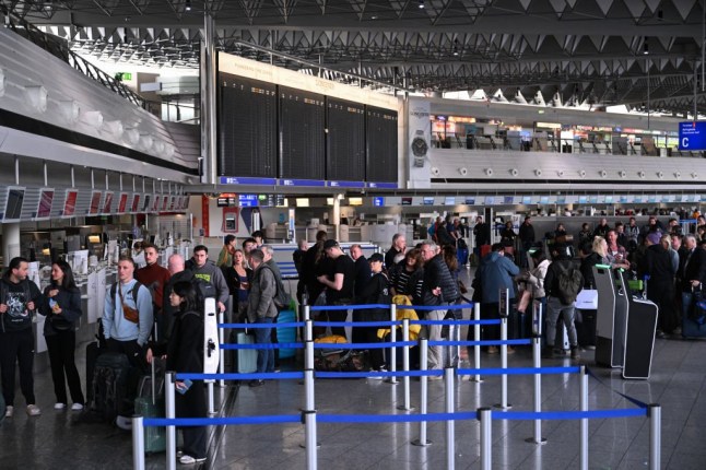 Passengers queue for rebooking as a large display is switched off (C back) at Frankfurt Airport