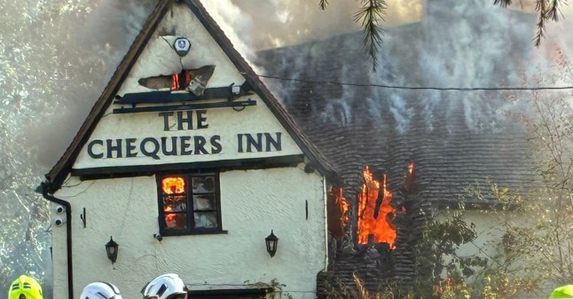 The burning Chequers Inn pub with bright red flames visible
