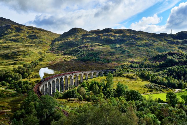UK, Scotland, Highlands, Glenfinnan viaduct with a steam train passing over it