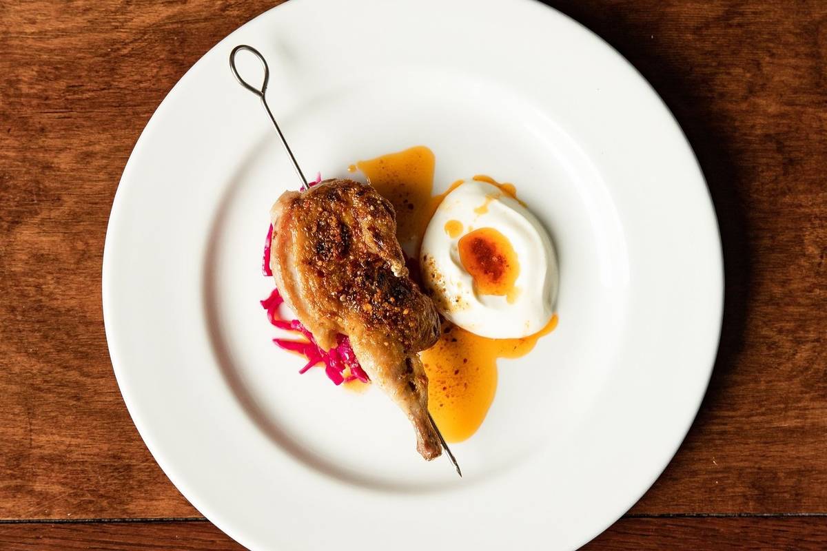 a plate with a portion of skewered chicken and a bright white dollop of sauce with chilli oil