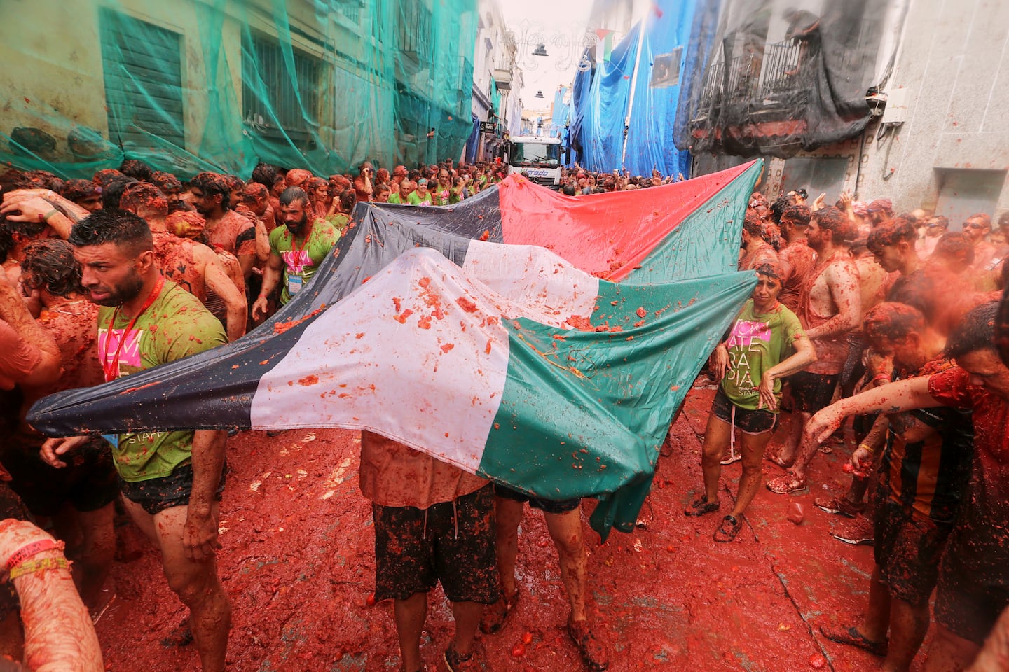 Revelers held a Palestinian flag as they threw tomatoes at each other during the annual "Tomatina" tomato fight fiesta, in the village of Bunol.