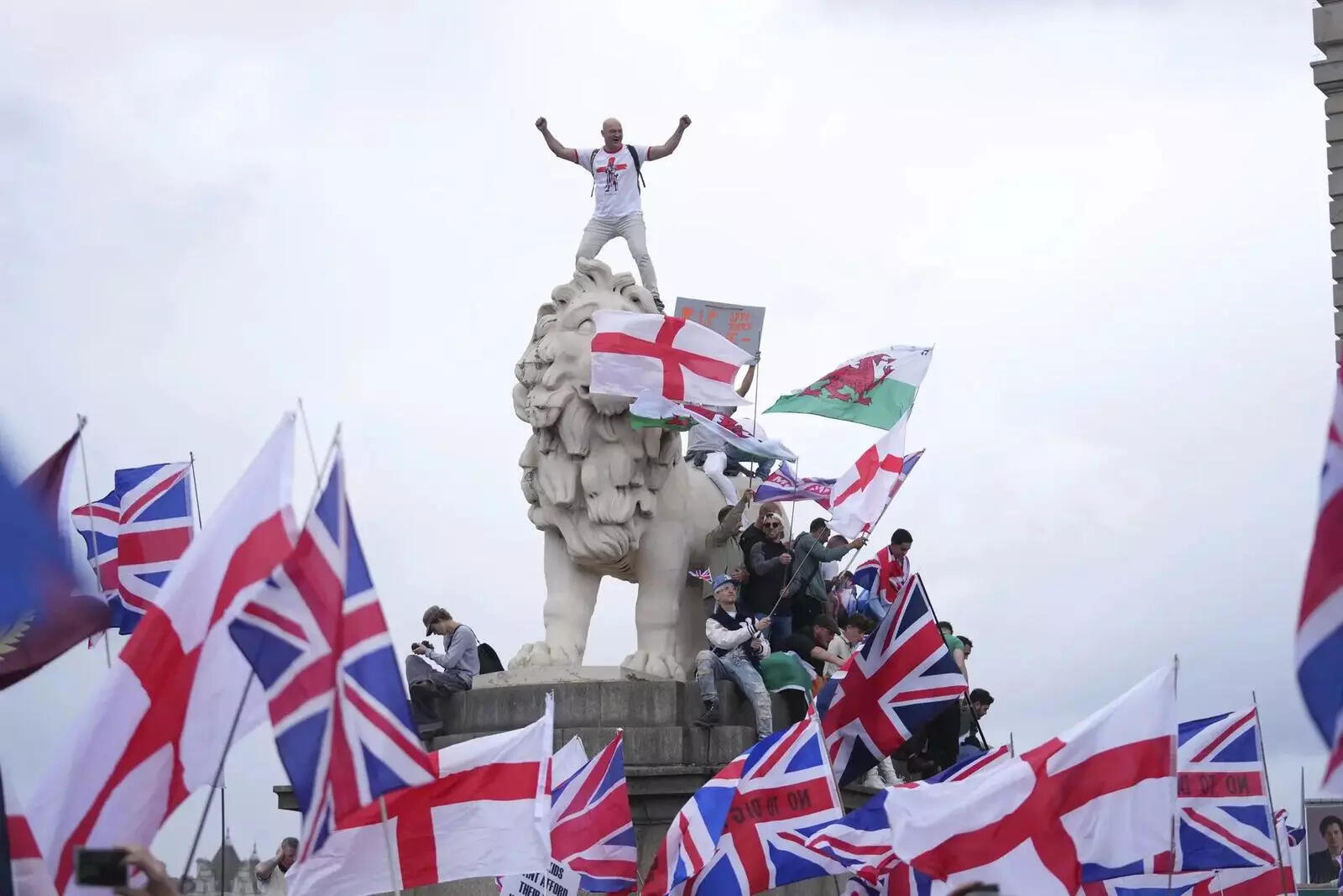 A demonstrator stands on the head of one of the lions of Westminster Bridge during a Tommy Robinson-led Unite the Kingdom march and rally in London, Saturday September 13, 2025.