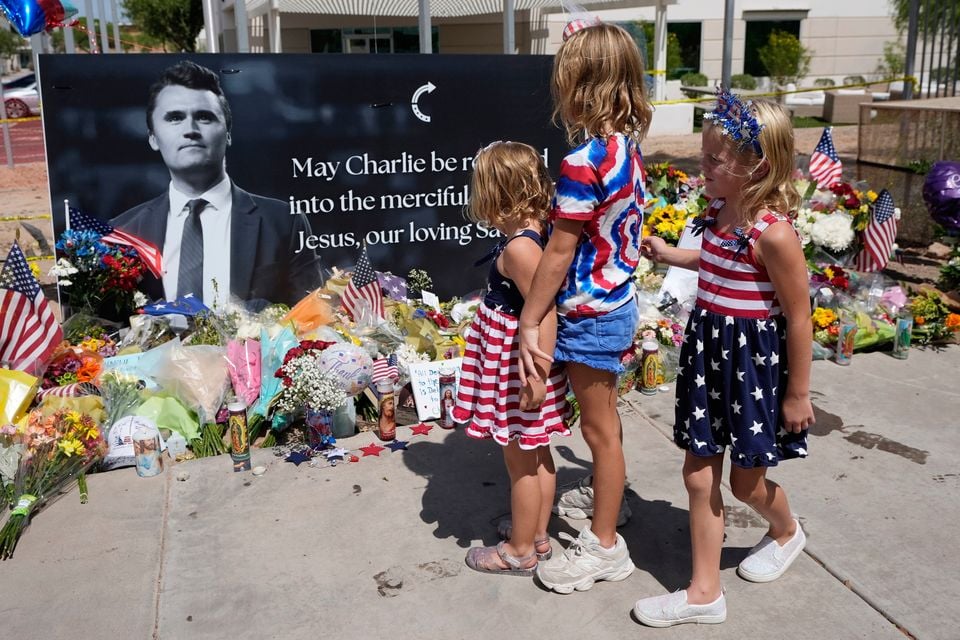 Sisters Clara Hetland (4), left, Haddie Hetland, centre (9), and Audra Hetland (6), of Surprise, Arizona, spend time at a makeshift memorial set up at Turning Point USA headquarters. AP Photo/Ross D. Franklin.