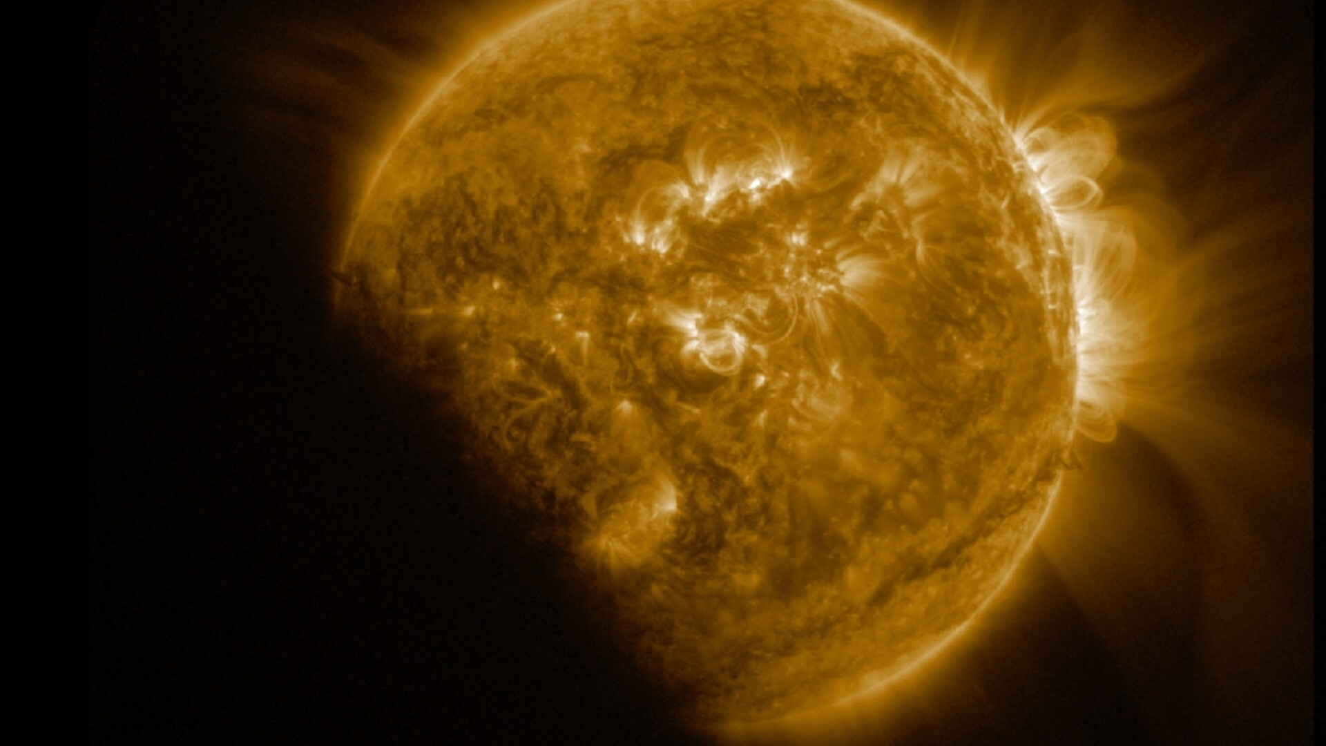 An image of the sun in space, with a dark shadow partially covering it where the moon crosses in front of it