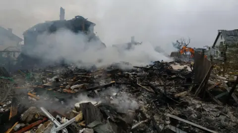 SERGEY DOLZHENKO/EPA-EFE/Shutterstock Ukrainian rescuers work at the site of a residential area struck by a rocket as a result of an overnight strike in a village near Kyiv, Ukraine.