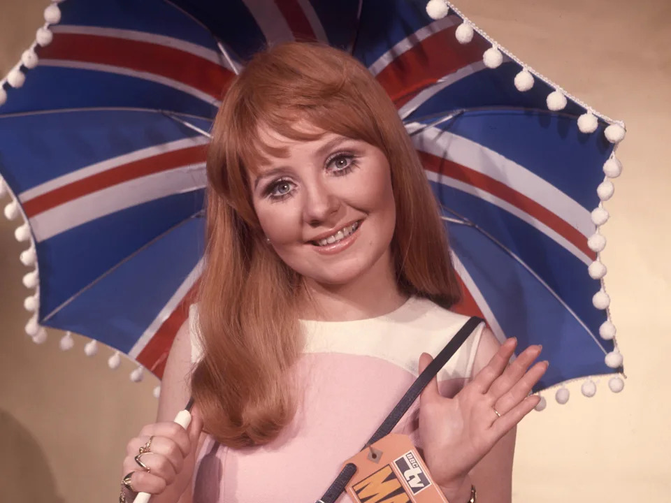 British singer Lulu holding Union Jack umbrella, circa March 1969; attached to her bag a BBC TV 'Madrid' large tag as she will represent the UK in the Spain Eurovision Song Contest with song 