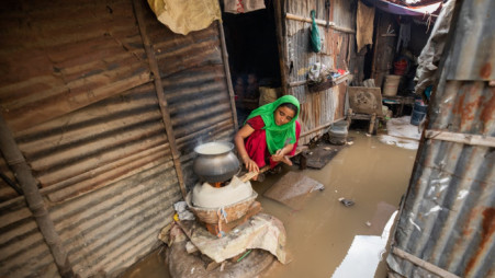 A woman seen grappling with flood water while working in a make-shift kitchen in the Kallyanpur Pora (burnt) Basti. Photo: Rajib Dhar/TBS