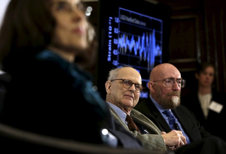 Rainer Weiss and Kip Thorne sitting in front of a monitor showing a display of a blue signal traced on a graph
