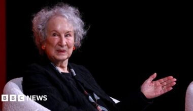 Woman points with her left hand while wearing a black ensemble