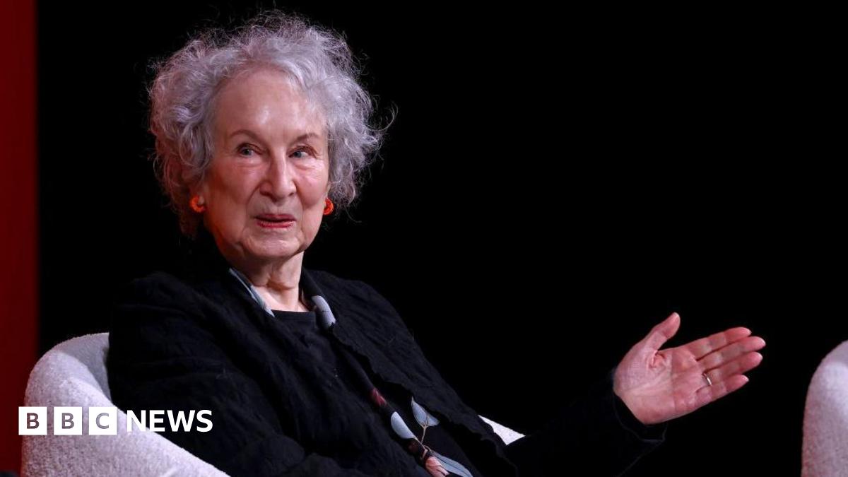 Woman points with her left hand while wearing a black ensemble