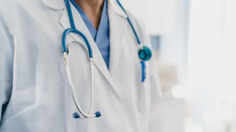 Getty A doctor wearing a white lab coat with a stethoscope. 