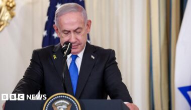 Netanyahu at a podium wearing a suit, looking down.