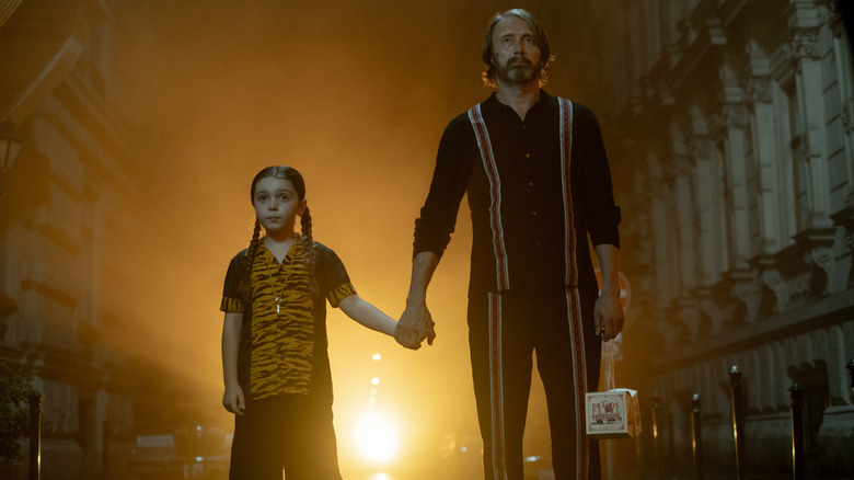 Sophie Sloan as Aurora and Mads Mikkelsen as her assassin companion holding hands in Dust Bunny