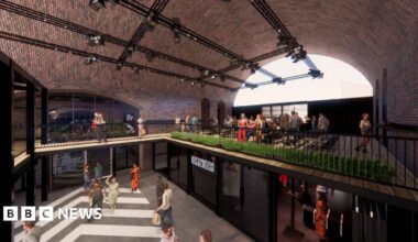 A CGI of a food and retail space under railway arches, with people walking around and sitting in a open two-level space with iron railings on the second floor.