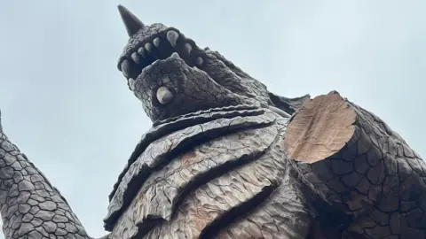 The picture was taken underneath the dragon.  The image clearly shows the missing arm. The picture was taken on a cloudy day.