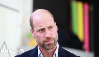 Prince William looks to the right of the camera, he is wearing a light blue shirt with a navy blazer.