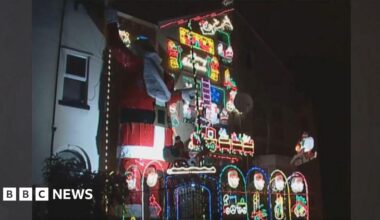 A three storey house decorated in Christmas lights with a giant Father Christmas