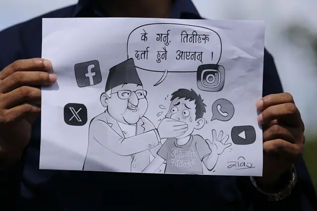 A Nepali protester holds up a sign showing a drawing of an elderly man covering the mouth of a younger man against a background of social media logos