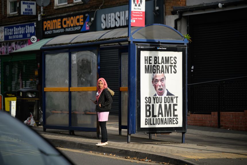 An advert on a nearby bus stop in Birmingham criticizes Farage's anti-immigrant rhetoric.