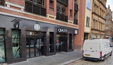 The exterior of Graces, a bar with black walls and windows, displaying "Graces" in white letters, located on a city street.