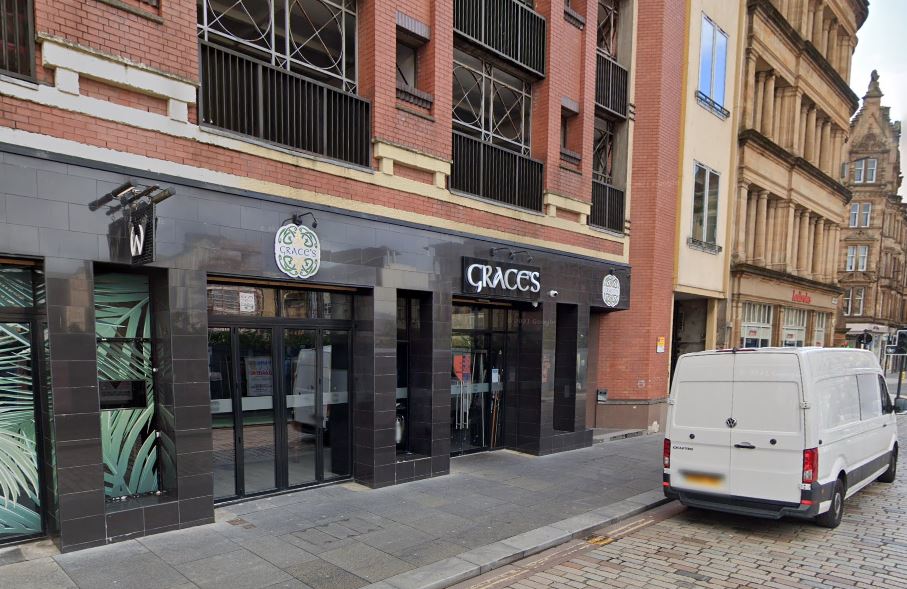 The exterior of Graces, a bar with black walls and windows, displaying "Graces" in white letters, located on a city street.