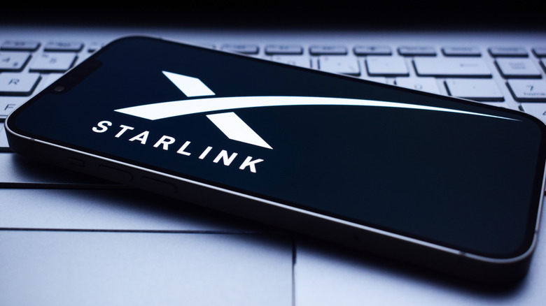 The Starlink logo shown on a smartphone that's placed on top of a laptop keyboard.