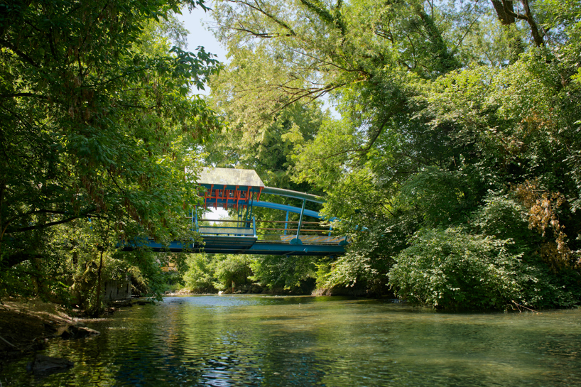 coral-toned timber and mirror canopy by GRRIZ transforms footbridge above river in france