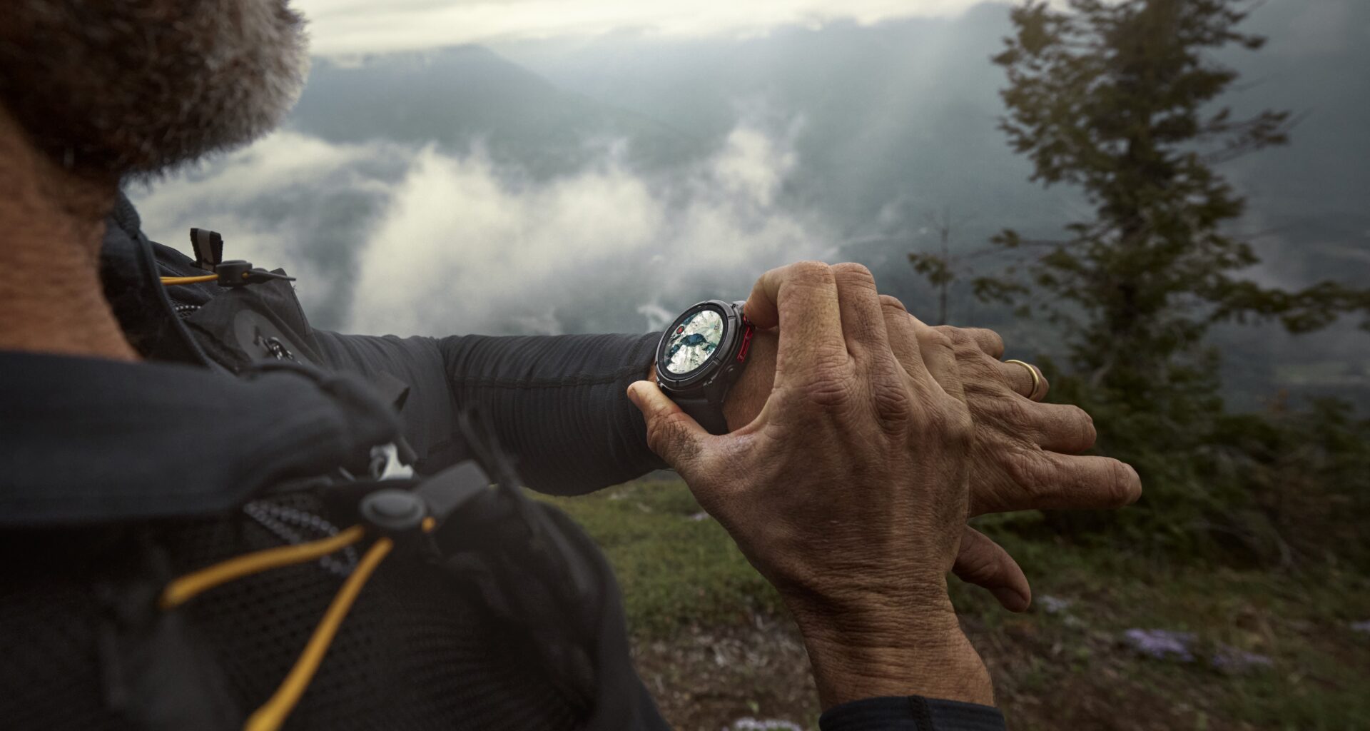 A photo of a man in the mountains wearing a Garmin Fenix 8 Pro, using it to check his nearby mapped location.
