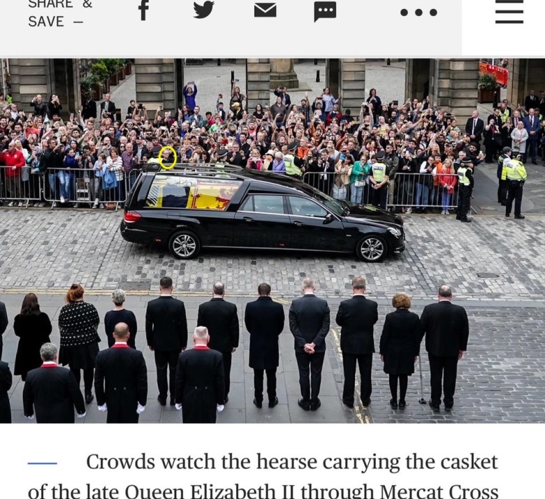 A hearse in front of a crowd of people.