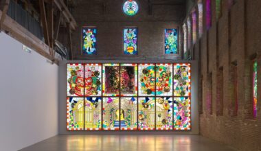 an installation by Raul de Nieves of a colorful lightbox mural with deities and skeletons along with smaller window fitted pieces