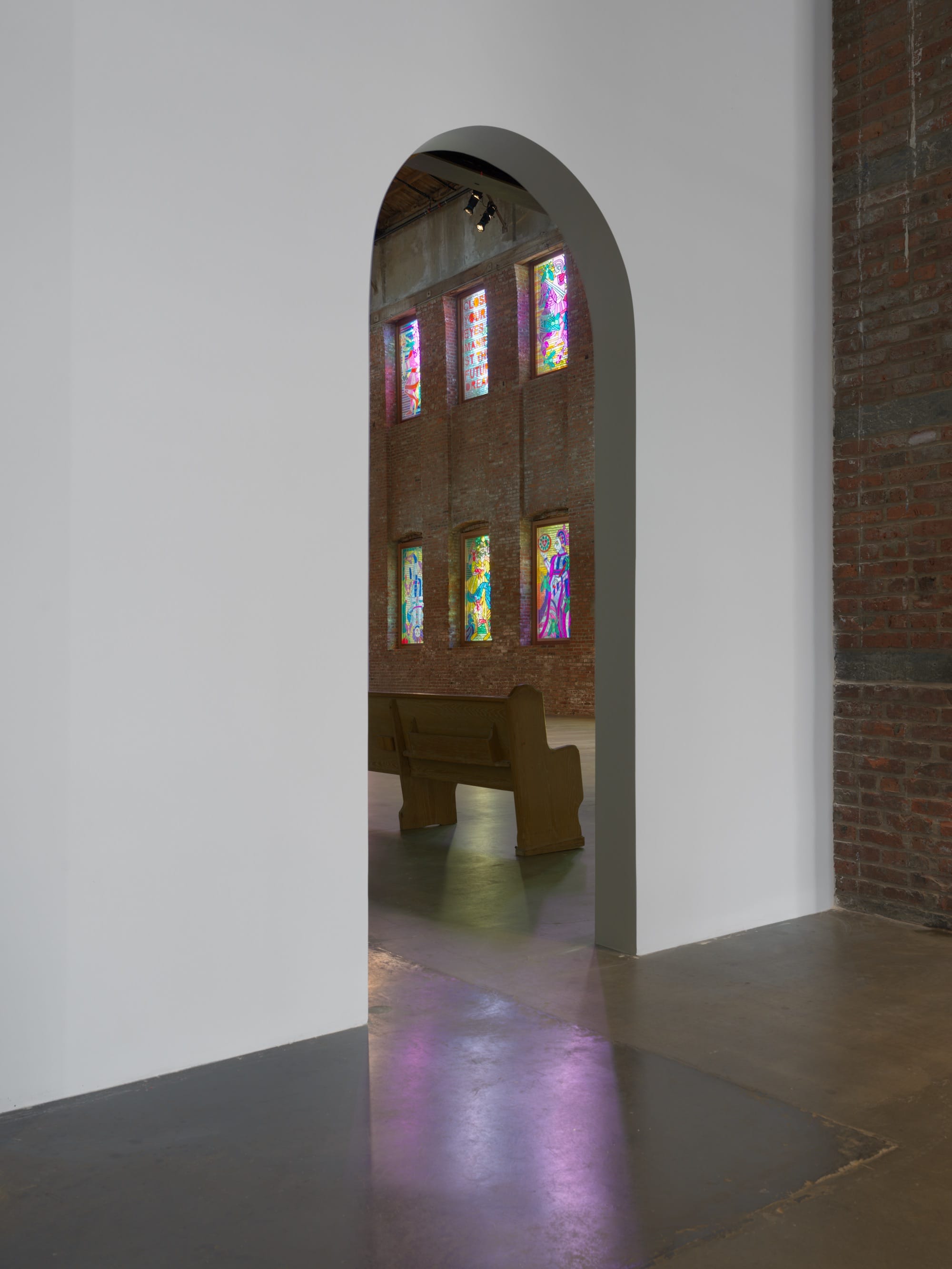 an installation by Raul de Nieves of a colorful window fitted pieces with typography and spiritual imagery