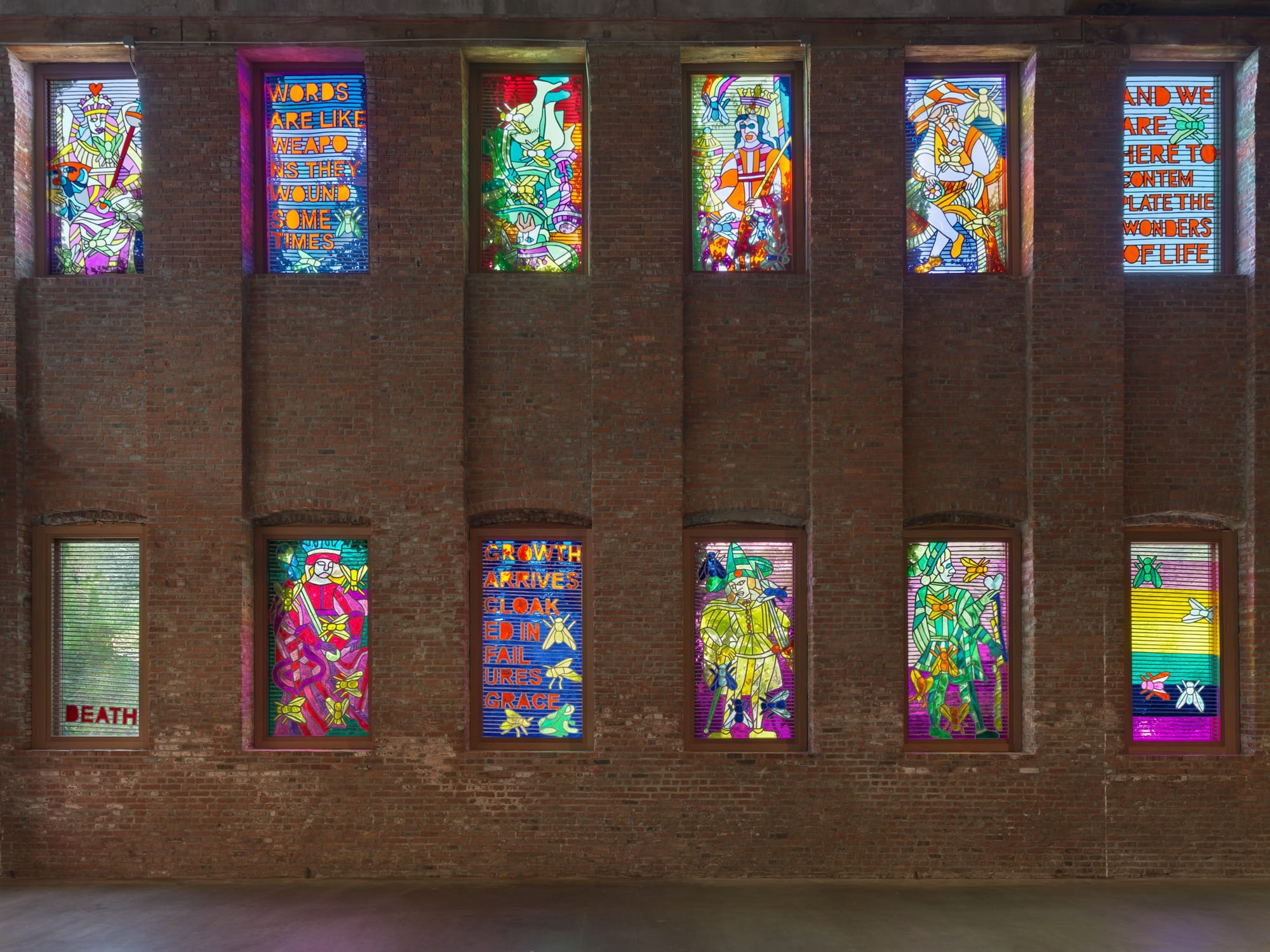 an installation by Raul de Nieves of a colorful window fitted pieces with typography and spiritual imagery