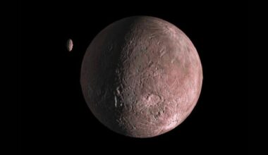 A small reddish rocky planet is seen in the darkness of space with a smaller planet-looking object nearby