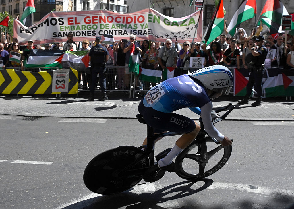 Pro-Palestinians protesters wave Palestinian flags as Team Israel Premier Tech's Israeli rider Nadav Raisberg competes during the 18th stage of the Vuelta a Espana, a 26 km race against the clock between Valladolid and Valladolid, on September 11, 2025. (Photo by Miguel RIOPA / AFP)