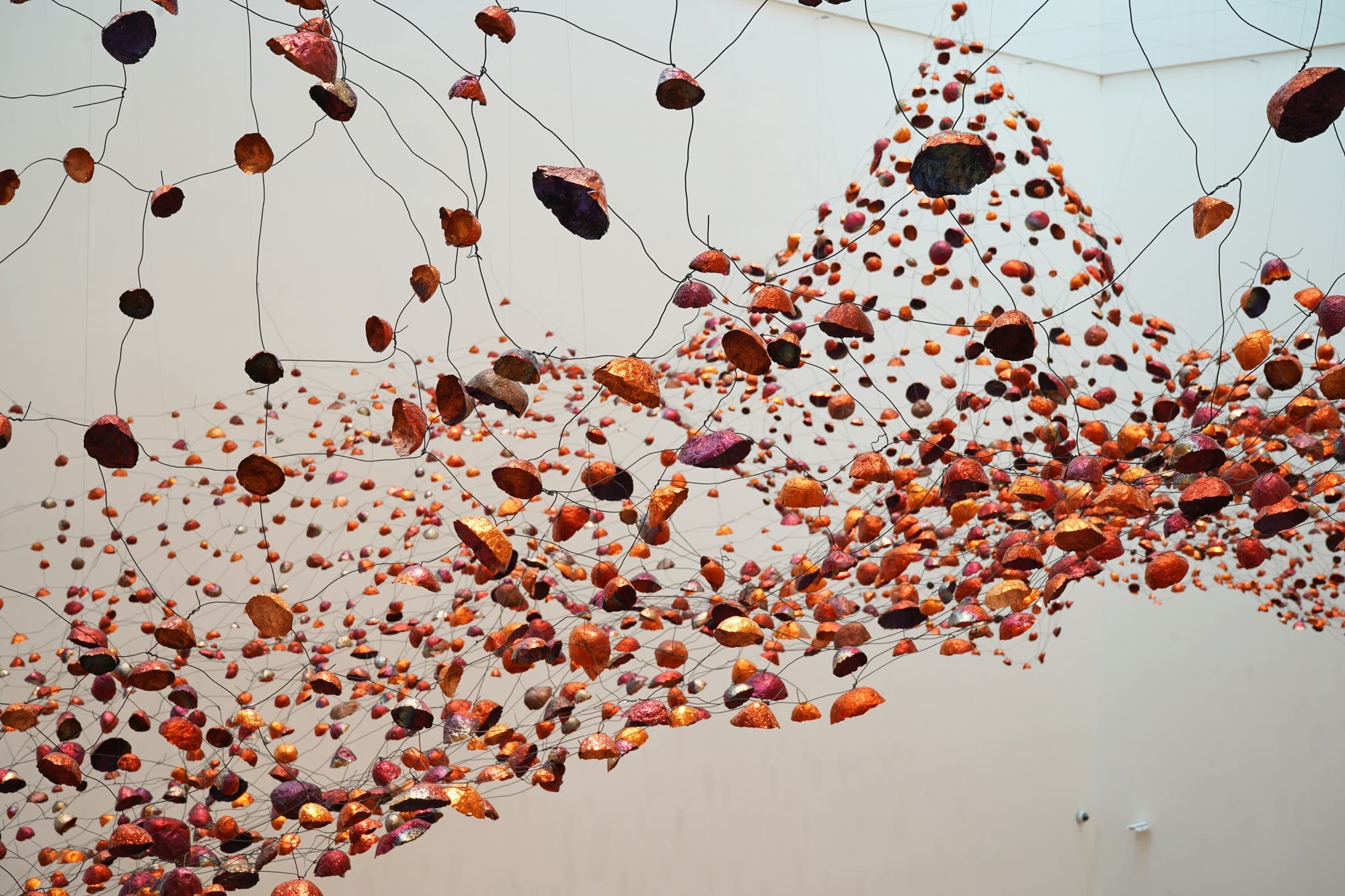 a detail of an installation view of a room-size installation by Yasuaki Onishi made of hundreds of copper forms connected by wire