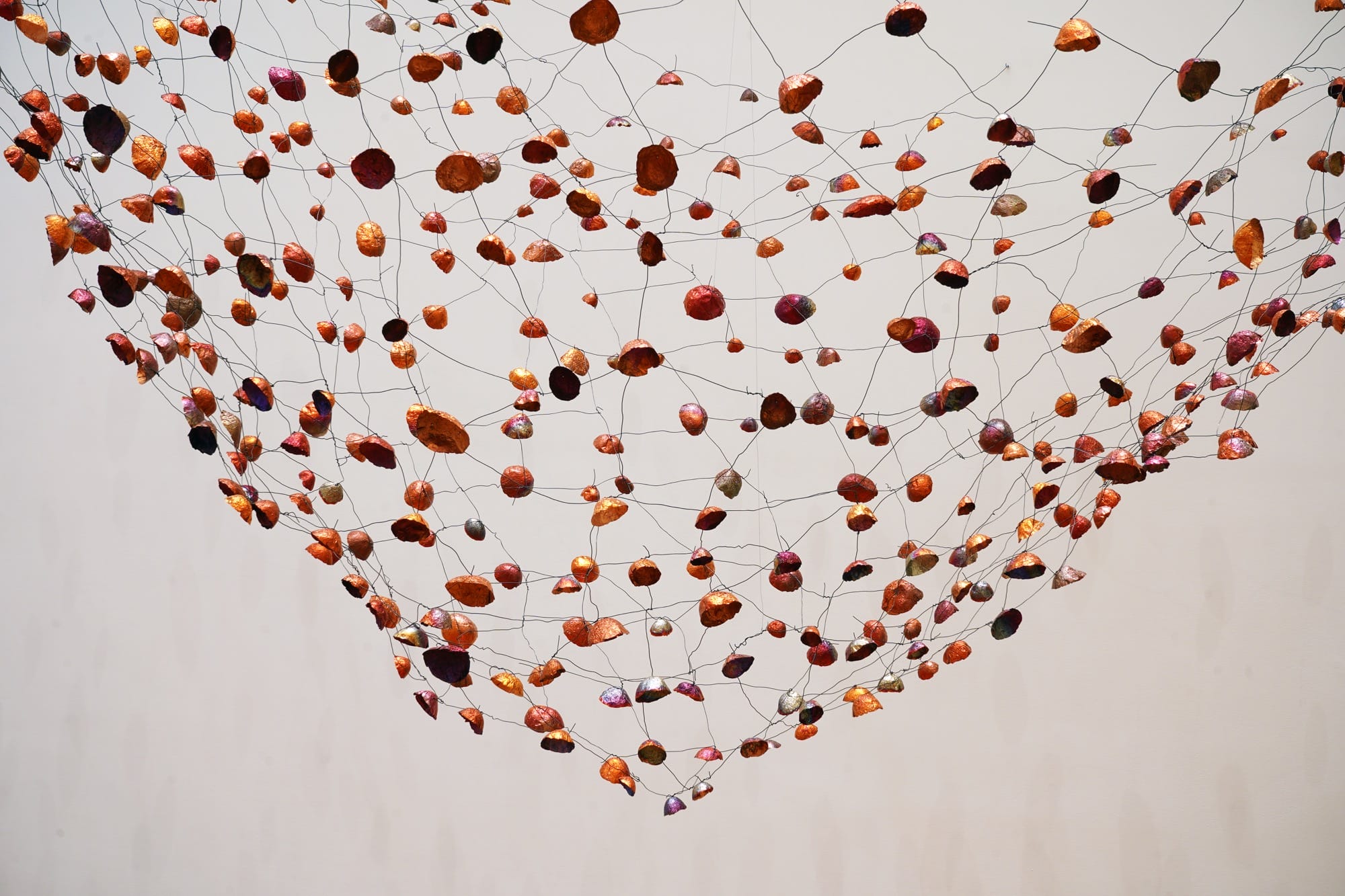 a detail of an installation view of a room-size installation by Yasuaki Onishi made of hundreds of copper forms connected by wire