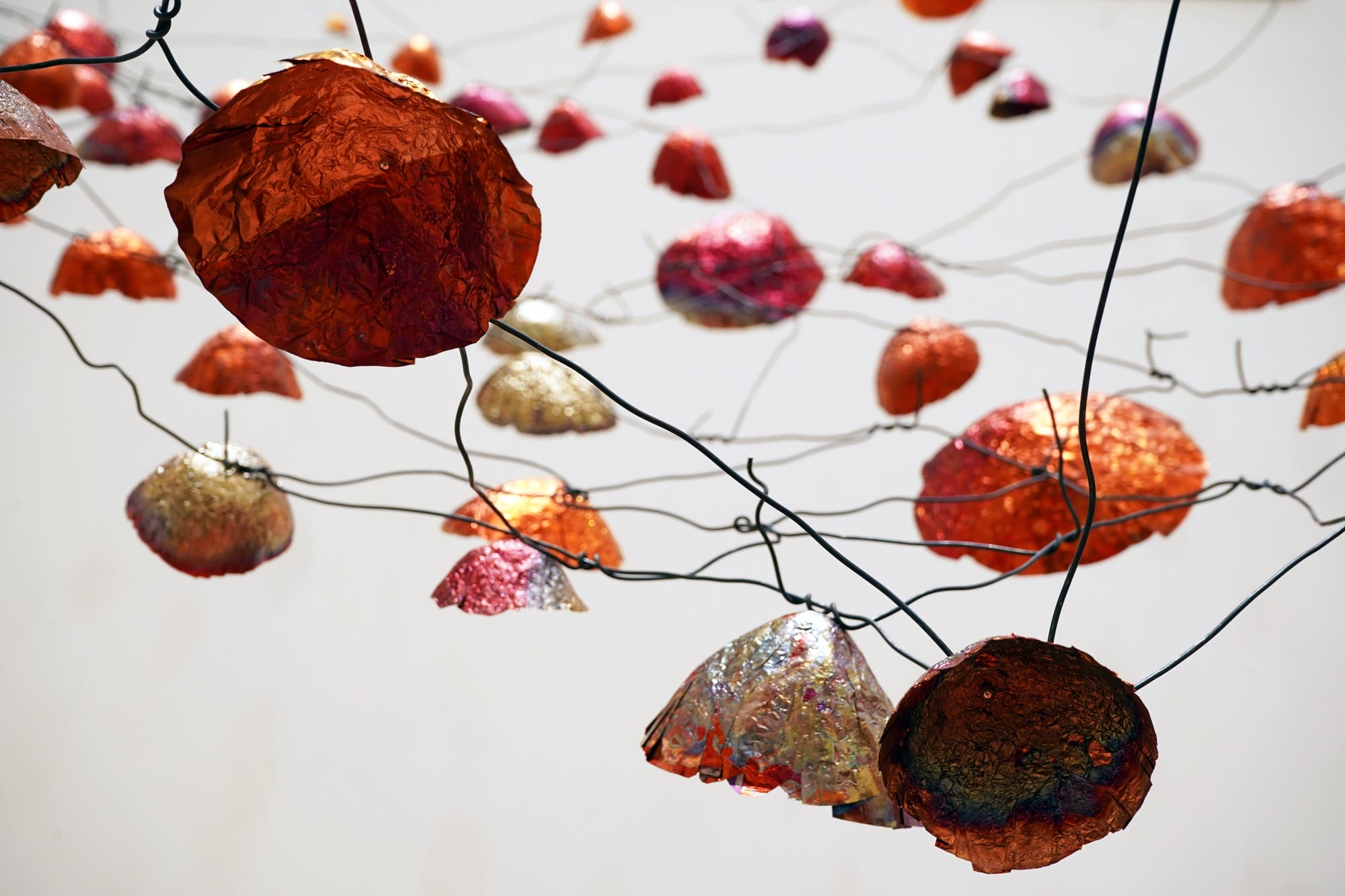a detail of an installation view of a room-size installation by Yasuaki Onishi made of hundreds of copper forms connected by wire