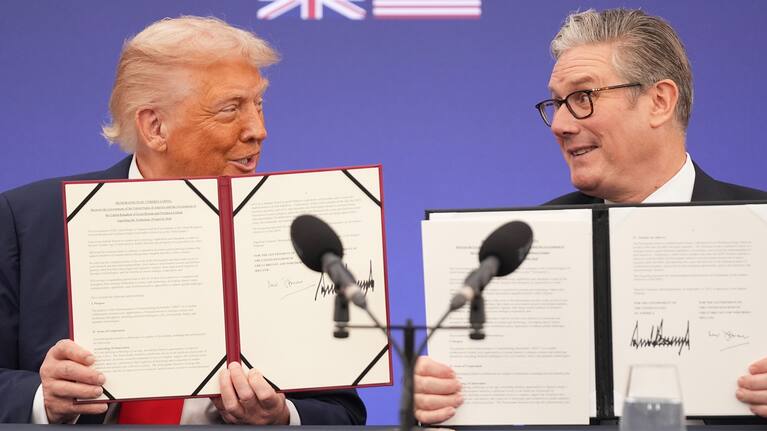President Donald Trump and Britain's Prime Minister Keir Starmer smile, holding a memorandum of understanding between the governments of the two countries.