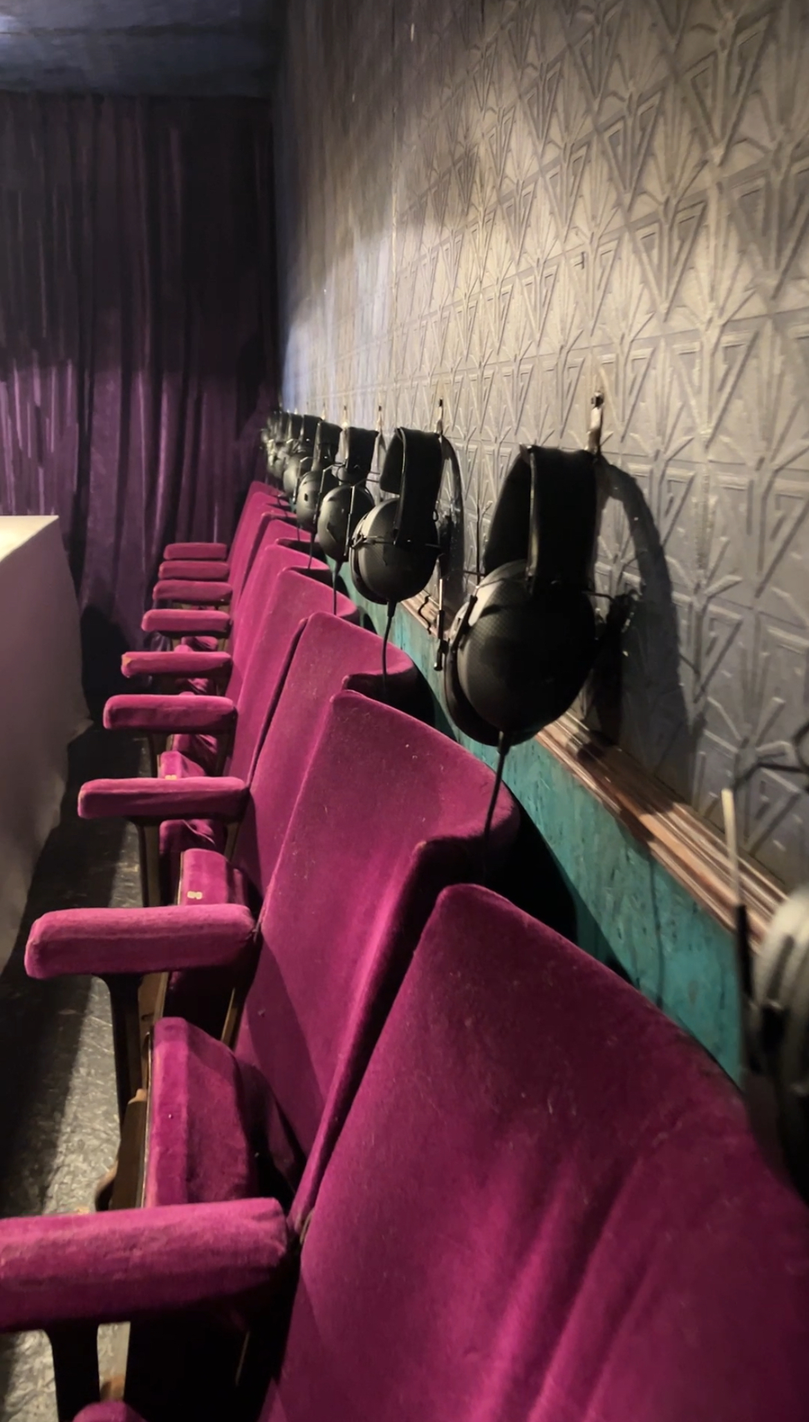 rows of velvet seats with headphones above