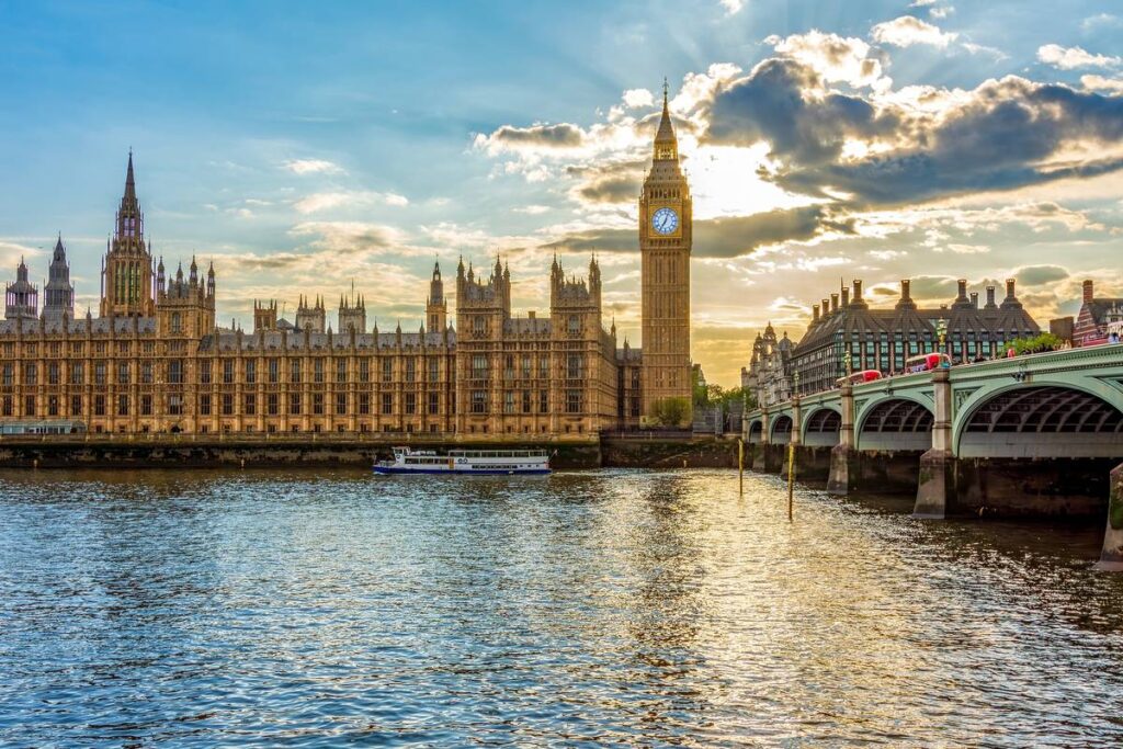 the sun setting behind big ben and the houses of parliament in london