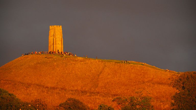 The early evening sunlight hits Glastonbury Tor in Somerset, as people gather in hope of seeing the blood moon. Pic: PA
