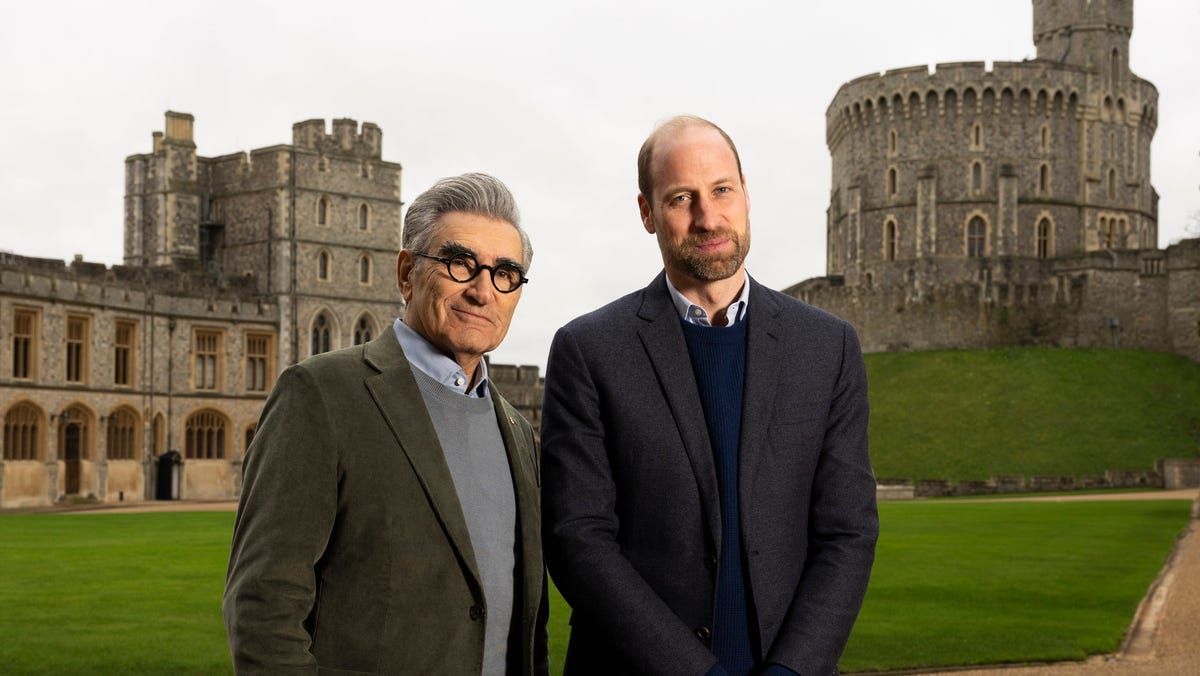 Two men walking on a path with a dog in a park setting.