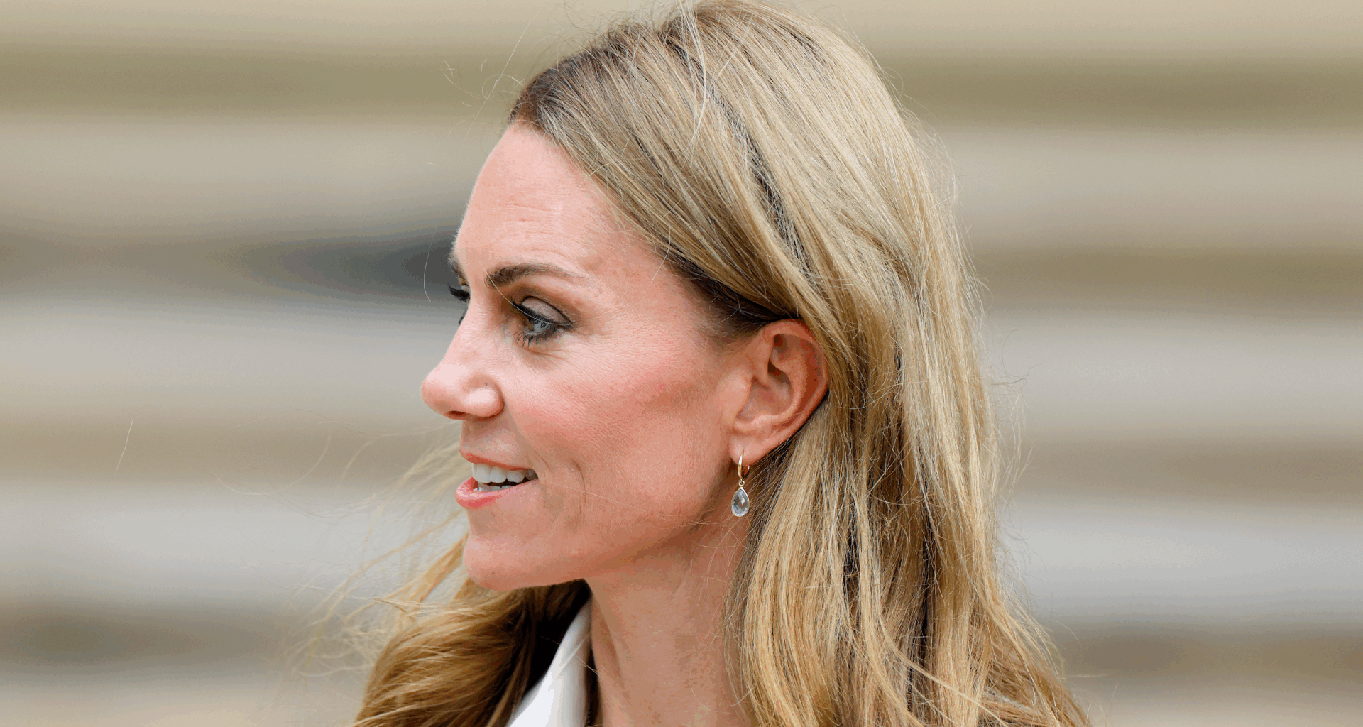 Kate Middleto smiling and turning her head to the side in front of a staircase