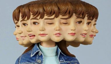 a detail of a wooden sculpture by Yoshitoshi Kanemaki of a female figure with a bright pink skirt and a denim jacket, with multiple faces and expressions